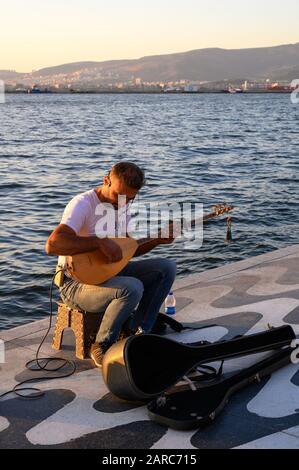 Uomo che suona un saz, un tradizionale strumento musicale turco, sul lungomare di Kordon a Izmir, Turchia Foto Stock