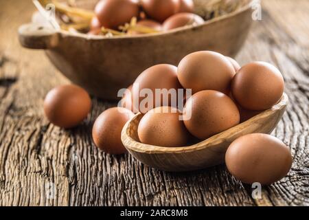 Uova fresche crude in ciotola di legno su tavola rustica di legno Foto Stock