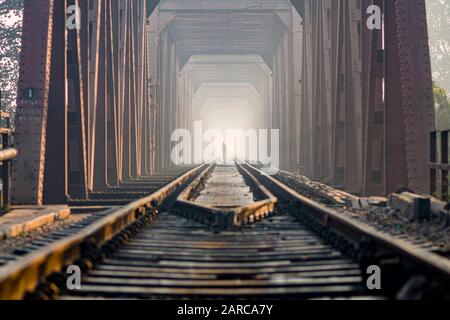 Lavoratore che cammina lungo il ponte ferroviario che attraversa il fiume Yamuna Foto Stock