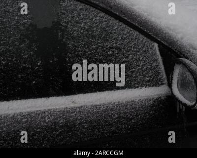 un finestrino e uno specchio per auto coperti da ghiaccio e neve Foto Stock