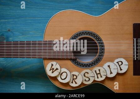 Chitarra su sfondo di legno teal con pezzi di legno su di esso scritta la parola: Culto Foto Stock