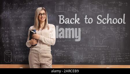 Insegnante di sesso femminile davanti a una lavagna con testo a scuola Foto Stock