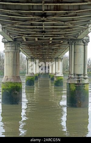 Vista sul Tamigi da sotto il ponte ferroviario Kew, Londra, Regno Unito, costruito in ferro. A bassa acqua, rivelando il metodo di costruzione. Foto Stock