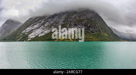 Colori freddi Norvegia fiordo scenico nebbia pesanti nuvole paesaggio con acqua fredda. Spettacolare vista panoramica nel nord della scandinavia estiva. Viaggia verso nord bac Foto Stock