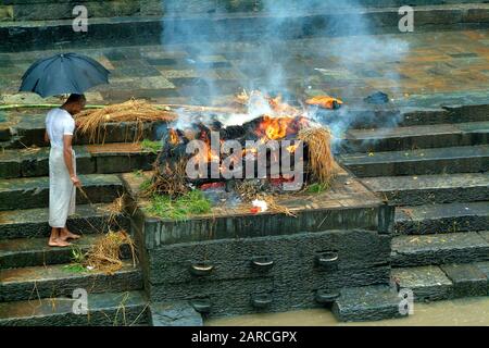 Kathmandu, Nepal - 15 luglio 2004: Sacerdote non identificato dai funerali tradizionali in Pashupatinath sul fiume Bagmati Foto Stock