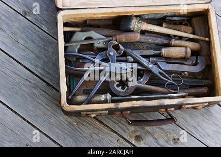 Vecchia valigia con i diversi attrezzi manuali sulle tavole di legno Foto Stock