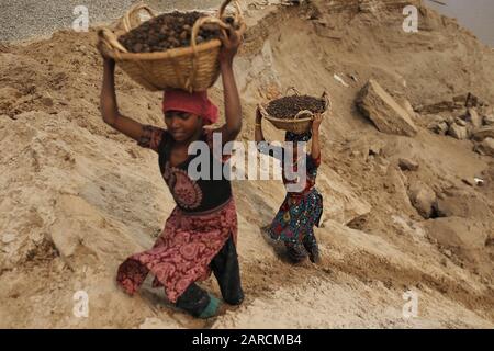 Sylhet, Bangladesh. 27th Gen 2020. Da sinistra, Suma (10) e Rotna (10), portare pietre raccolte sulla loro testa in un sito di cava sulla riva Dholai fiume a Bholaganj, Sylhet. Tutti i lavoratori di età lavorano qui in condizioni molto pericolose senza alcuna attrezzatura di sicurezza per salari bassi. Credit: Md Mehedi Hasan/Zuma Wire/Alamy Live News Foto Stock