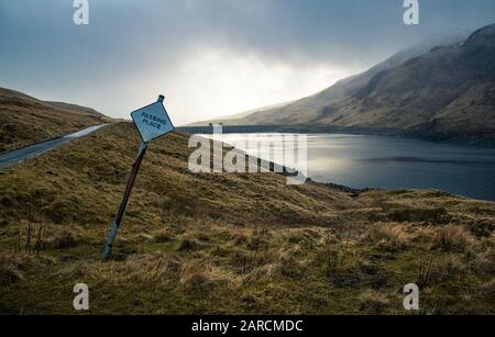 Passando il cartello con la riserva d'acqua Lochan na Lairige sullo sfondo delle Highlands scozzesi. Foto Stock