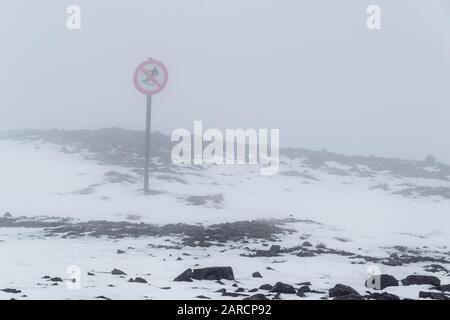 Rosso 'No skiing' segno in nebbia profonda su una pista da sci vuota a Glen Coe, Scozia. Foto Stock