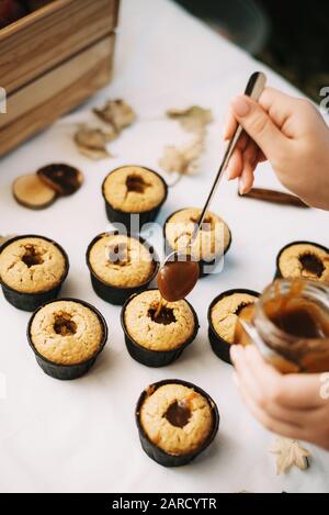 Il panettiere crea i tortini in stampi. Riempimento con biscotti fatti in casa caramello liquido. Foto Stock