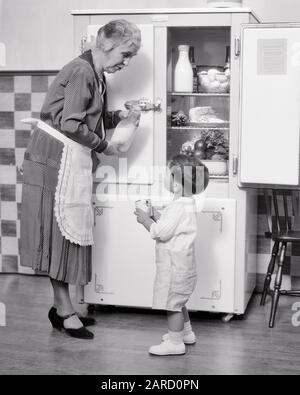 1930S TODDLER CHE CHIEDE LA NONNA PER LA TAZZA DI LEVARSI IN PIEDI DAVANTI AL FRIGORIFERO - F1652 HAR001 HARS GIOVANE SNACK NONNI GIOIA LIFESTYLE ANZIANI FEMMINE GRANDGENITORE HEALTHINESS HOME VITA LATTERIA COPIA SPAZIO FULL-LENGTH SIGNORE CHE CHIEDE ALLE PERSONE CHE SI PRENDONO CURA DEI MASCHI ADULTI ANZIANI B&W ANZIANO ANZIANO ANZIANO DI ETÀ WELLNESS OLDSTER BEVANDA FLUIDO NONNE ANZIANI COLLEGAMENTO NIPOTE DI FRONTE AL BAMBINO RAGAZZO COOPERAZIONE CRESCITA NOVELLAME PROTEINE INSIEME BEVANDE NERO E BIANCO ETNIA CAUCASICA NONNA HAR001 VECCHIO STILE Foto Stock