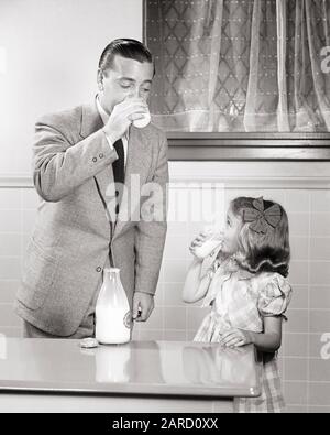 1940S PADRE E FIGLIA IN CUCINA BERE BICCHIERI DI BOTTIGLIA DI VETRO DEL LATTE SUL TAVOLO UOMO INDOSSARE VESTITO RAGAZZA UN ABITO CONTROLLATO - F4967 HAR001 HARS GIOVANE ADULTO GIOCO DI SQUADRA FAMIGLIE GIOIA STILE DI VITA DONNE SALUTE HOME VITA LATTIERO-CASEARIO COPIA SPAZIO AMICIZIA METÀ-LUNGHEZZA FIGLIE PERSONE PRENDERSI CURA MASCHI PADRI B&W OBIETTIVI VESTITO E CRAVATTA FELICITÀ BENESSERE BEVANDA E CONTROLLATO CONCORSO PAPÀ FLUIDO NUTRIZIONE ORGOGLIO CONNESSIONE CONSUMARE IDRATAZIONE ALIMENTAZIONE ALIMENTAZIONE ALIMENTAZIONE ALIMENTAZIONE ALIMENTAZIONE ALIMENTAZIONE ALIMENTAZIONE AFFETTO COOPERAZIONE CRESCITA NOVELLAME PROTEINE RINFRESCANTE INSIEME GIOVANE ADULTO BEVANDE UOMO NERO E BIANCO Foto Stock