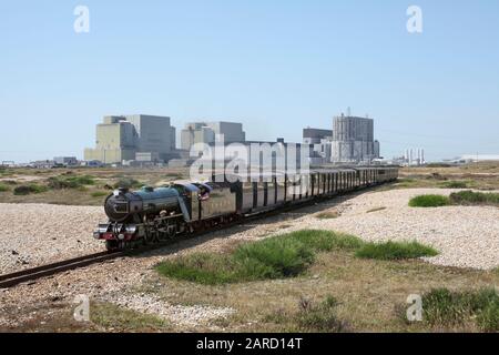 Un treno a vapore sulle Ferrovie Romney, Hythe e Dymchurch si dirige a est da Dungeness, con le centrali nucleari di Dungeness A & B sullo sfondo. Foto Stock