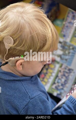 Un ragazzo con gli apparecchi acustici e impianti cocleari Foto Stock