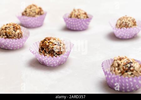 Sane caramelle naturali crude fatte di frutta secca, noci e vari semi su sfondo grigio neutro Foto Stock