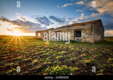 Tramonto che illumina un fienile tradizionale nella campagna siciliana, Italia Foto Stock