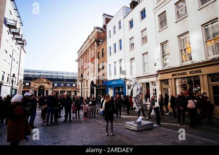 Un performer di strada si bilancia su una vanga a Covent Garden, Londra Foto Stock
