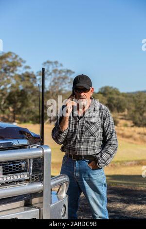 Uomo su telefono cellulare con vista paddock, accanto alla parte anteriore del camion con antenne Foto Stock