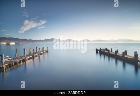 Due pontili in legno o banchine e il lago di sunrise. Torre del Lago Puccini, Versilia, il lago di Massaciuccoli, Toscana, Italia, Europa Foto Stock