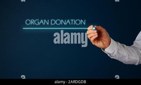Mano di un medico che scrive un segno di donazione di organo con penna glover su sfondo blu. Con spazio di copia. Foto Stock