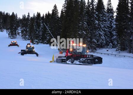 Tre veicoli per motoslitta in linea dopo il tramonto, in azione di preparazione sci per il giorno successivo, stazione sciistica di Kopaonik, Serbia Foto Stock