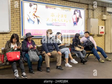 Passeggeri su piattaforma in attesa del treno della metropolitana, Kyoto, Giappone Foto Stock