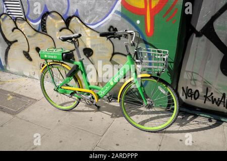 Bici elettrica lime-e appoggiata contro una parete graffiti, Londra, Inghilterra, Regno Unito Foto Stock