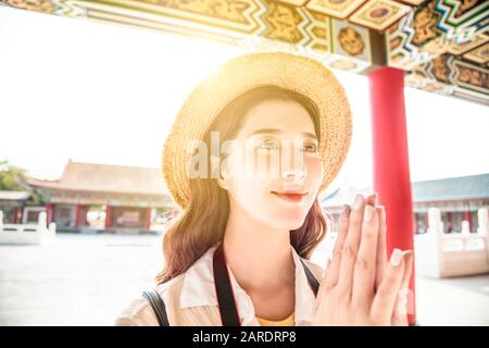 giovane donna turistica che prega al tempio cinese Foto Stock