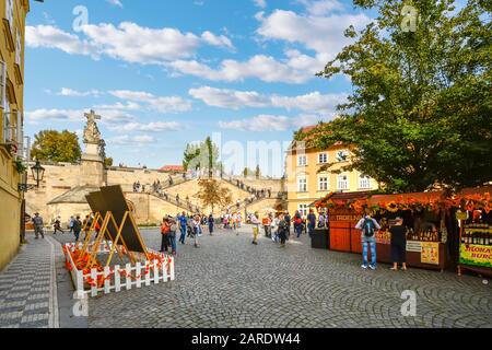 I turisti godono di una giornata di sole nella piazza del mercato con scale che collegano l'Isola di Kampa al Ponte Carlo a Praga, Repubblica Ceca Foto Stock