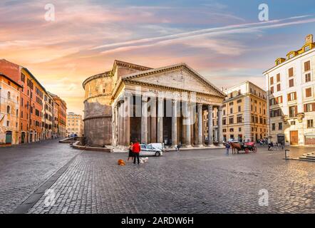 Gli italiani camminano i loro cani al mattino sotto un cielo colorato di fronte all'antico Pantheon in Piazza della rotonda, mentre una carrozza a cavallo attende Foto Stock