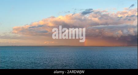 Immagine panoramica di una forte tempesta di pioggia e nuvole sulla costa della Danimarca con un arcobaleno che emerge sul Mar Baltico nel Nord Europa. Foto Stock