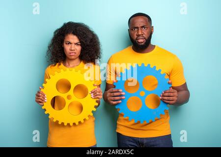 Giovane con ingranaggi su fondo azzurro. Concetto di integrazione europea e il partenariato Foto Stock