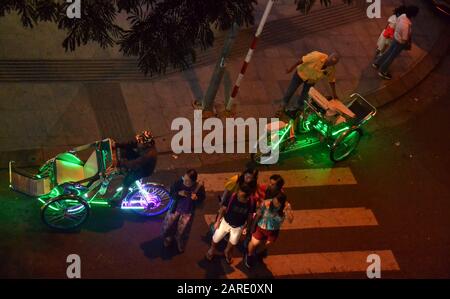 Una vista dall'alto dei taxi di bicicletta Illuminati o dei rickshaws a tre ruote di notte nella località balneare di Nha Trang in Vietnam, Asia sudorientale, Indochina, Asia. I taxi di bicicletta sono ora assistiti a motore e fanno pagare circa 25.000 dong vietnamiti o circa 1 dollaro al chilometro. Foto Stock