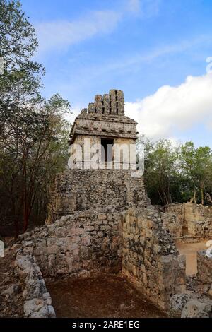 Le torreggianti rovine Della Struttura V poke sopra la parete di un piccolo edificio, piercing un cielo azzurro pallido nell'antica città Maya di Hochob, Messico Foto Stock