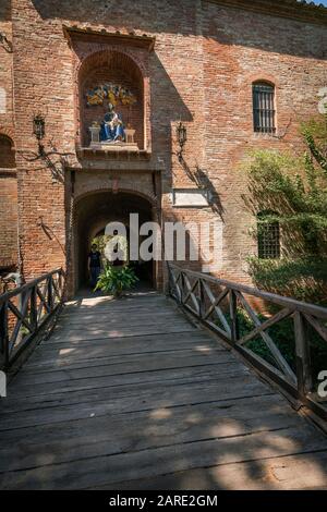 Asciano, Italia - i turisti camminano verso il ponte levatoio in legno che conduce al Monastero di Oliveto, Abbazia di Monte Oliveto maggiore Foto Stock