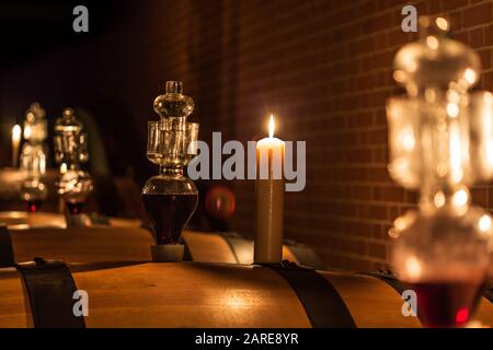 Fuoco selettivo di botti di vino con una candela accesa Foto Stock