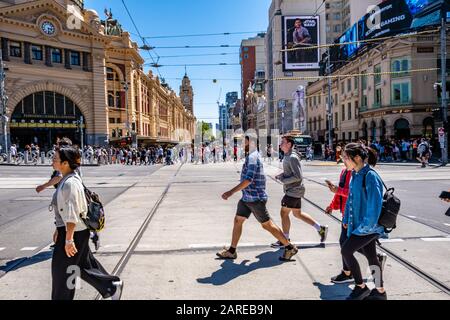 Melbourne, Australia - Circa Dicembre, 2019: Grande folla di persone che attraversano la trafficata Flinders Street nel CBD di Melbourne in una giornata di sole Foto Stock