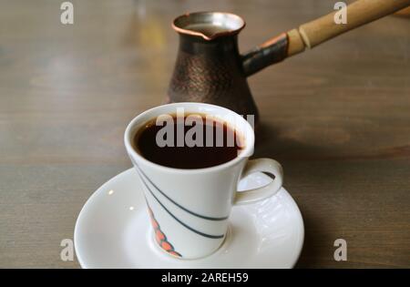 Tazza di caffè turco caldo con Caldaia da caffè su tavolo di legno Foto Stock