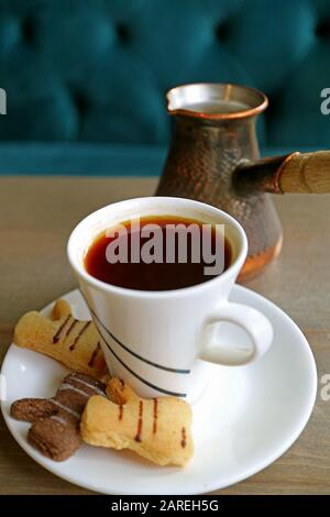 Immagine verticale di biscotti caldi di burro e caffè turco con La Caldaia Di caffè Sfocata in background Foto Stock