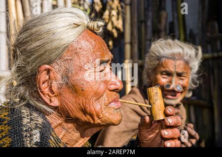 Ritratto di un vecchio Apatani indossando il tradizionale acconciatura con la maglia alla fronte, fumo tubo Foto Stock