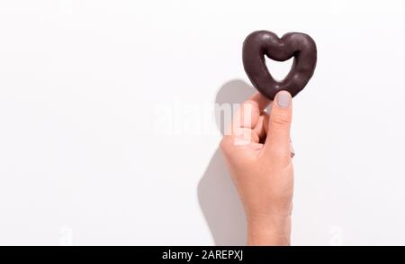 Biscotto a forma di cuore con mano femmina sopra il bianco Foto Stock