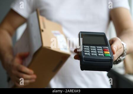 Il deliveryman maschio tiene il terminale POS in posizione di primo piano Foto Stock