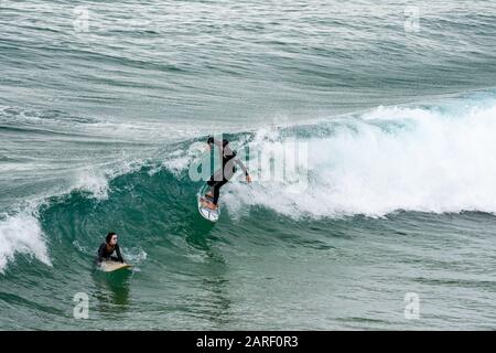 Sarges, Portogallo - 22 Gennaio 2020: Surfers catturano grandi onde sulla spiaggia di Praia do Beliche nella regione dell'Algarve in Portogallo Foto Stock