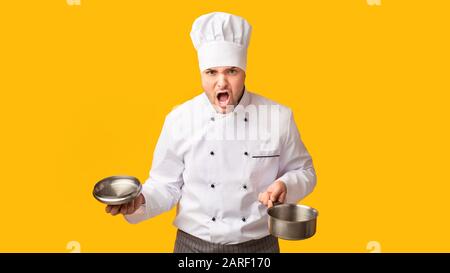 Arrabbiato Chef Gridando Tenendo Casseruola In Piedi Su Sfondo Giallo, Panorama Foto Stock