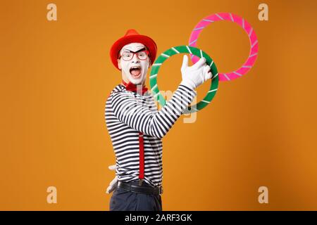 Clown happy mime con anelli multicolore su sfondo arancione vuoto Foto Stock