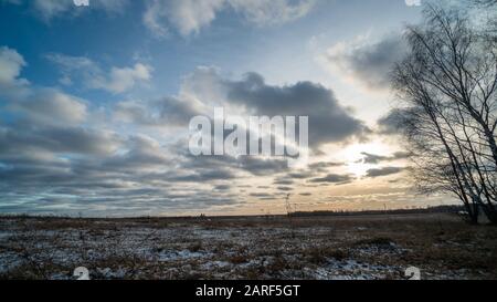 Bella impostazione del sole su campo ghiacciato Foto Stock