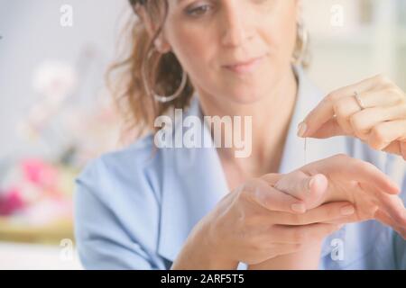 Terapista di agopuntura applicando aghi di agopuntura per il suo cliente la mano Foto Stock