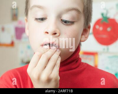 Ragazzo holding perso i denti decidui contro il suo disegno sulla parete Foto Stock