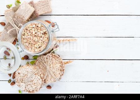 Bar con farinata d'avena, muesli, lino, spuntini sani. Su uno sfondo di legno bianco. Vista dall'alto. Spazio libero per il testo. Foto Stock