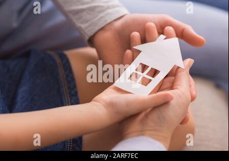 Primo piano di famiglia di tre casa di carta di tenuta in mani Foto Stock